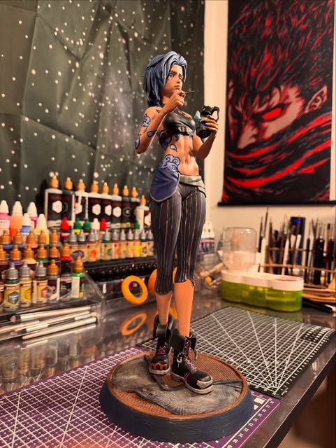 Hand-painted Jinx at the 3DPrintica workbench, surrounded by paints and tools